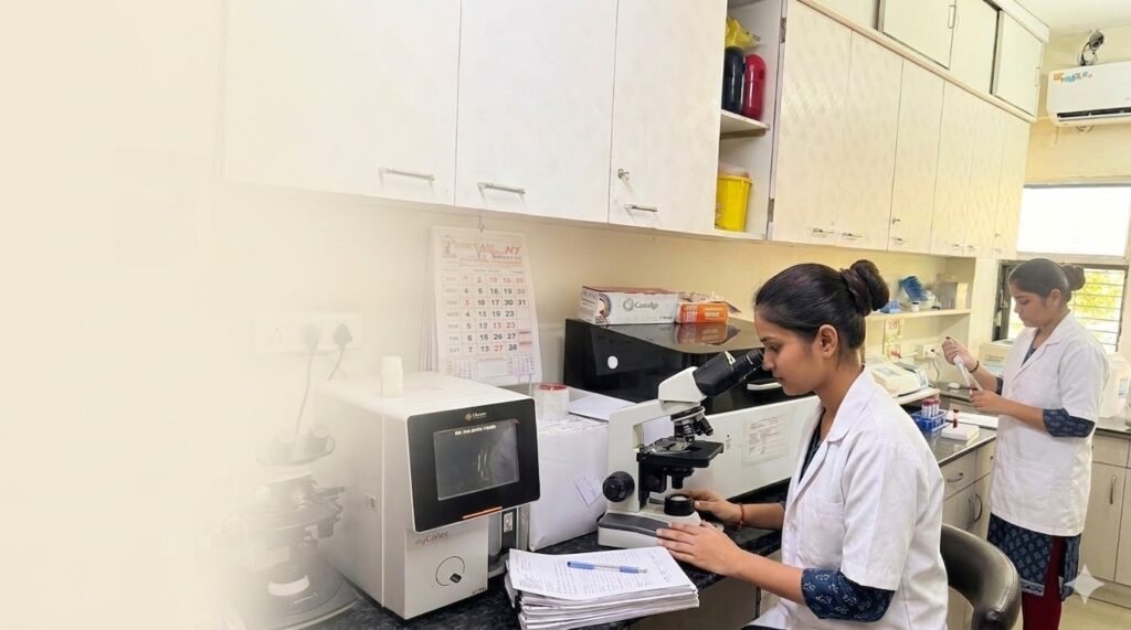 Technicians working in Vardhaman Pathology Laboratory analyzing samples using microscope and lab equipment